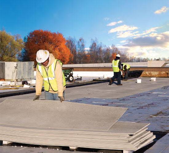 For a relatively small cost, roofing cover board protect the roofing insulation and membrane from the negative forces of fire, wind uplift, impact and hail, moisture, sound intrusion and foot traffic. Above, workers lay out 1/4