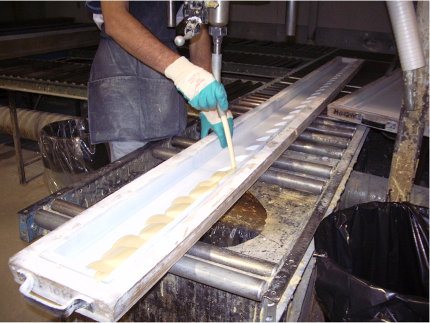 The mixed polymer is dispensed into the open-faced molds, coated with the first primer coat protection.