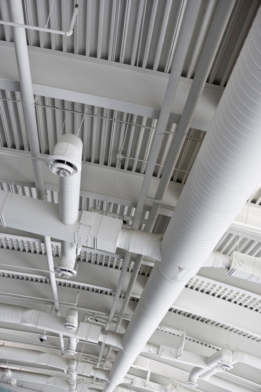 Photo of a ceiling with plumbing and structural obstructions.