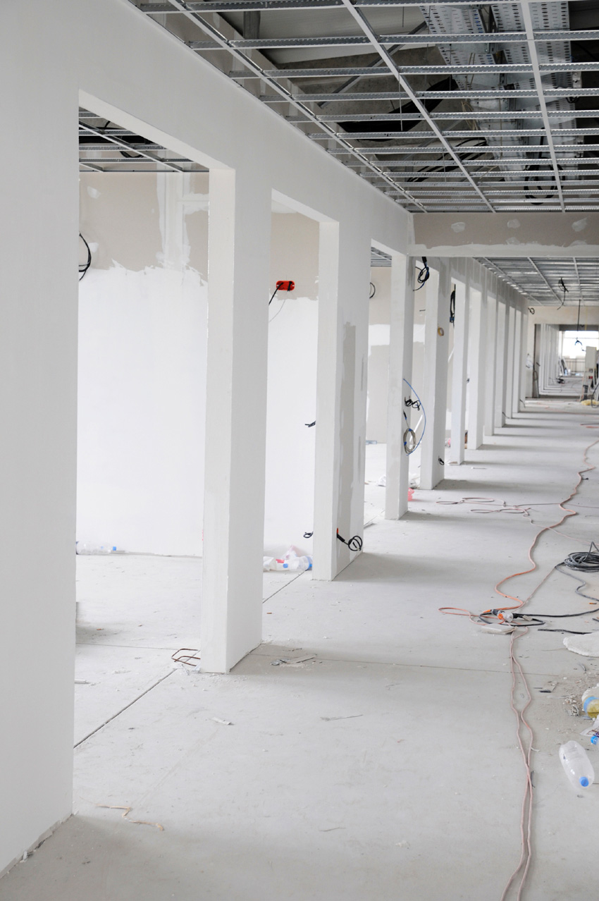 Photo of a room under construction with walls that extend above the ceiling grid.