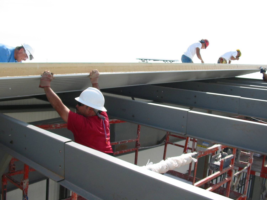 Photo of workers installing metal panels.