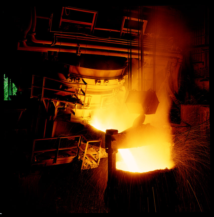 Shown is an electric arc furnace discharging molten steel into a ladle.