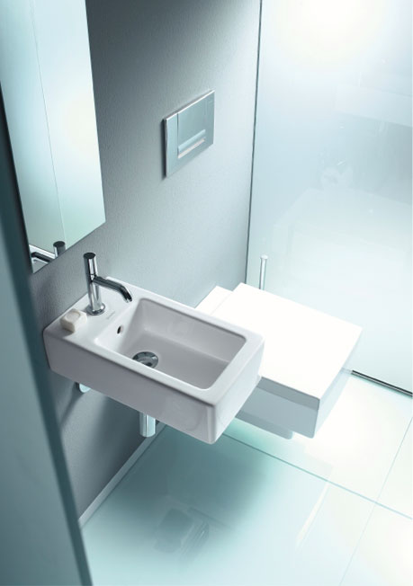 A wall mounted toilet with matching hand rinse basin in compact space.