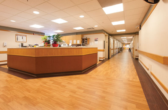 Nurses station and hallway at the Vernon Memorial Healthcare (VMH) medical building in Viroqua, Wisconsin. No-wax sheet vinyl flooring with the appearance of wood planks was chosen for performance characteristics as well as a warm, natural look.