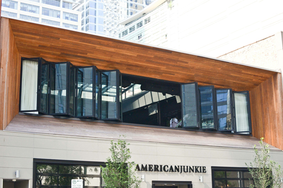 An expanse of folding glass windows admits natural light that adds to the appeal and energy efficiency at American Junkie restaurant.