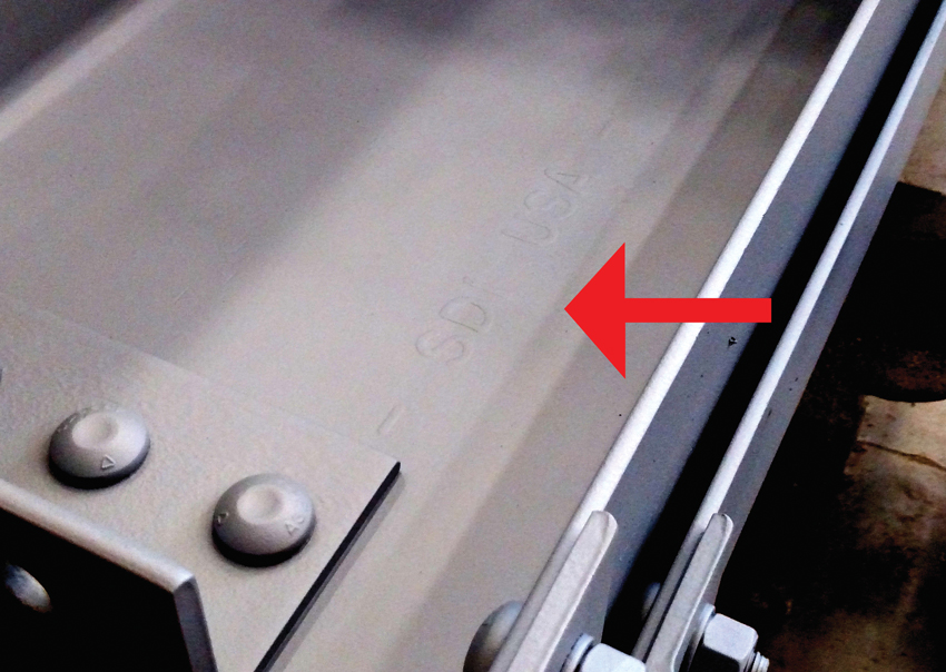 Mill marks from Steel Dynamics Inc. (SDI) are visible through the painted finish on this structural steel member.