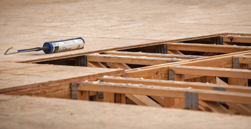 Photo of floor framing with applied adhesive.