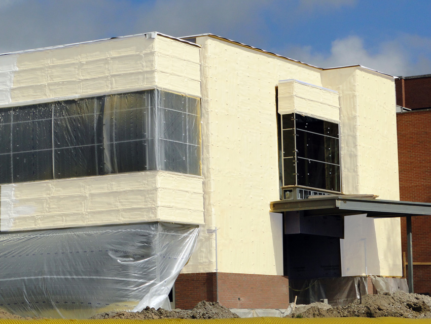 Photo of a building under construction with continuous spray foam insulation along its exterior walls.