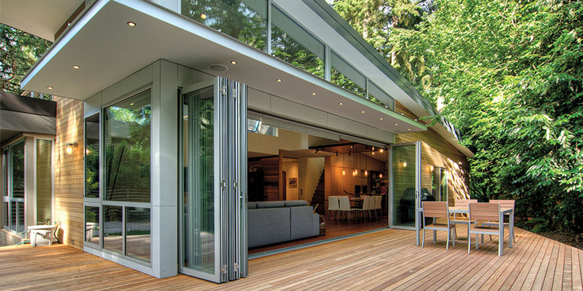 Multi-panel door systems eliminate barriers between interior and exterior spaces, creating a natural and open flow. Aluminum thermally broken folding doors showcase the beauty of surrounding landscaping at this home. 