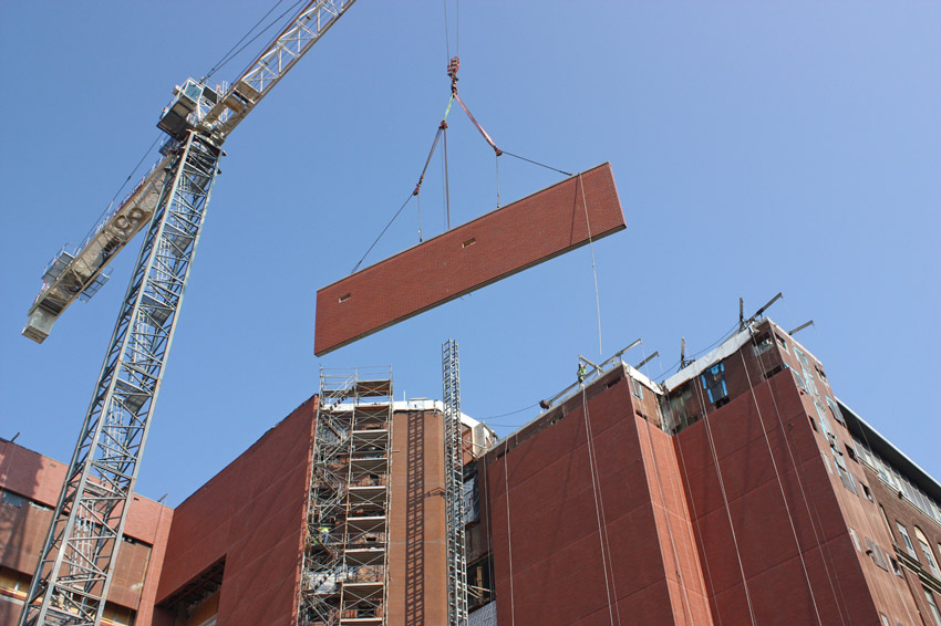 Lightweight concrete panels being lifted in place using equipment designed for this tight site footprint