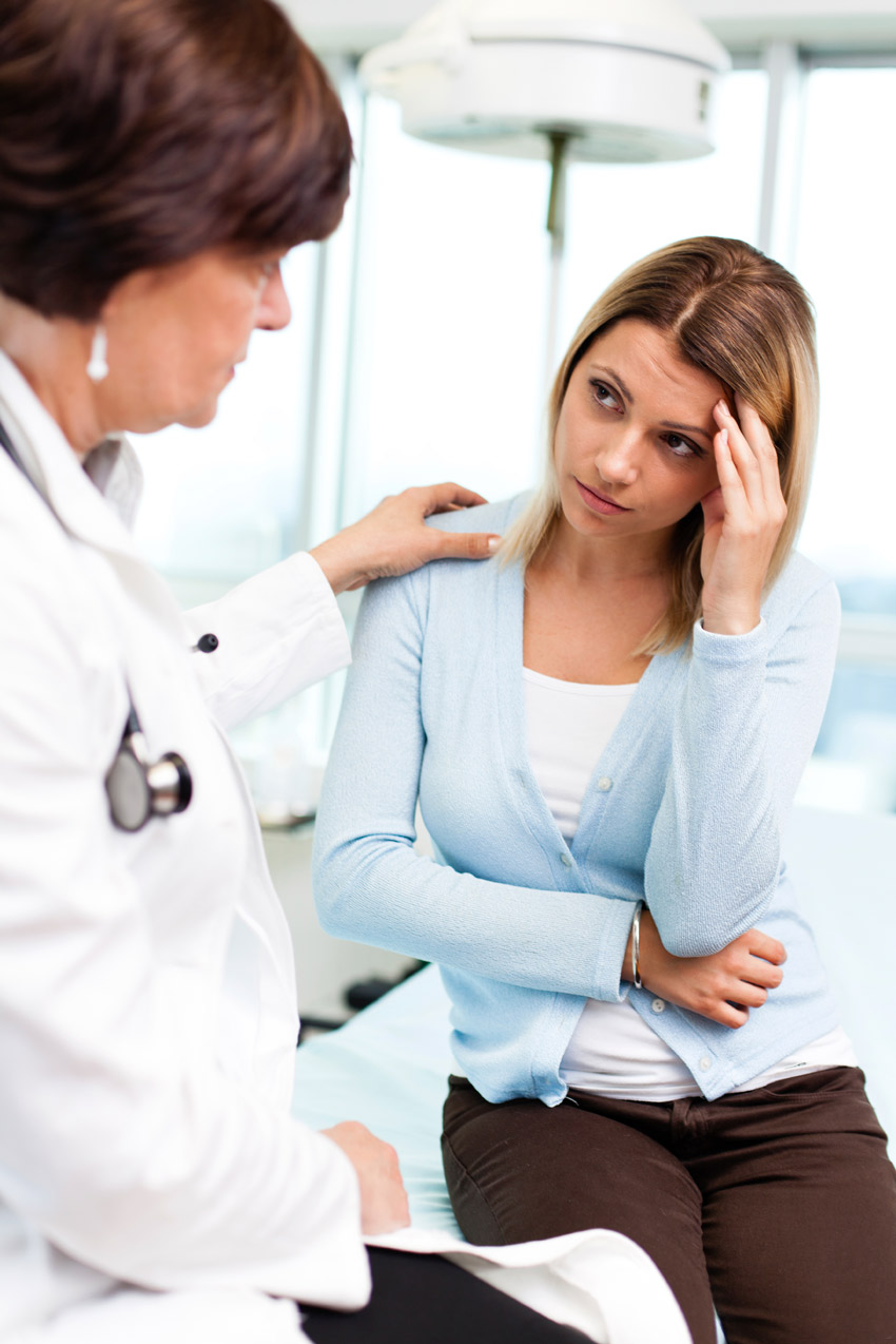 A patient holding her head and doctor touching her shoulder